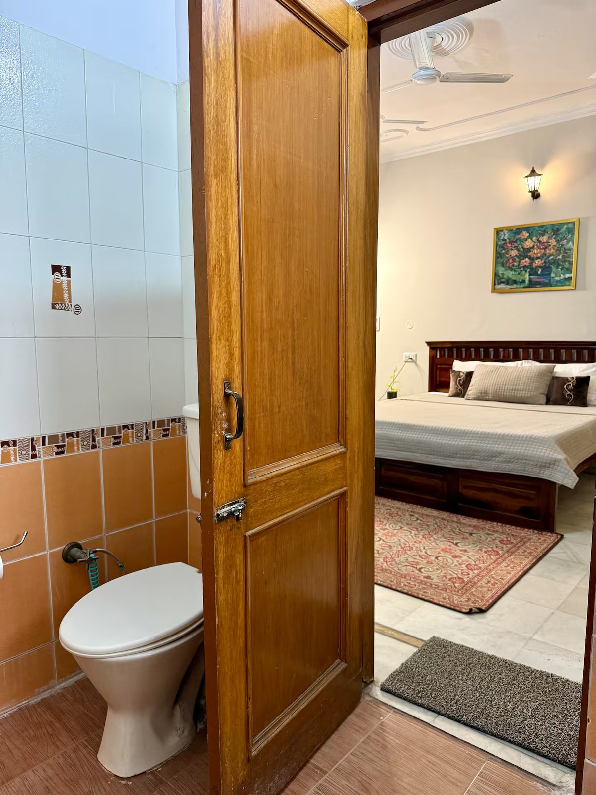 Bathroom with a white sink and faucet, wall-mounted soap dispenser, towel rack, water heater, tiled walls, toilet paper holder, and floor drain.