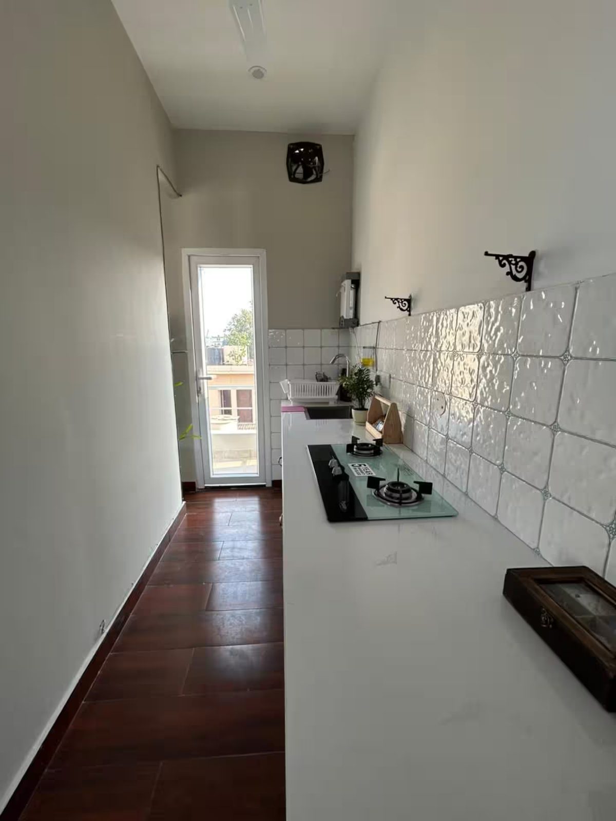 A bathroom with a toilet, vessel sink on a vanity, glass-enclosed shower, wall-mounted fixtures, frosted window, patterned wall tiles, and brown floor tiles.